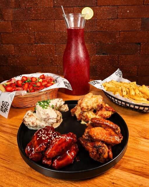 Mesa de Bajonazo con alitas de distintos sabores, papas y una jarra de refresco